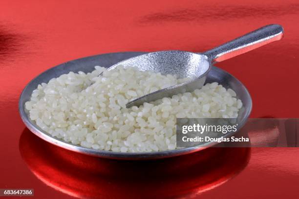 dish of uncooked white sushi rice on a red background - sushi train stock pictures, royalty-free photos & images