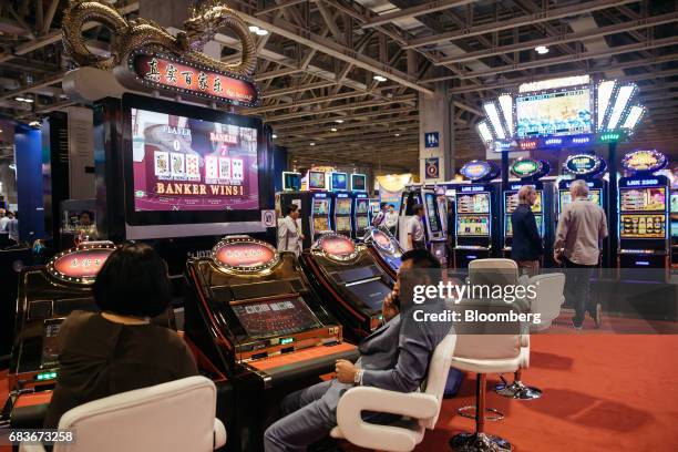 Attendees play a baccarat gaming machine at the Global Gaming Expo inside the Venetian Macau resort and casino, operated by Sands China Ltd., a unit...