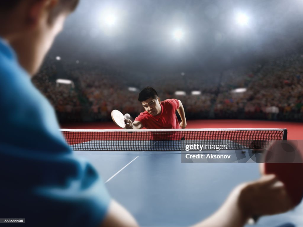 Two ping pong players play table tennis
