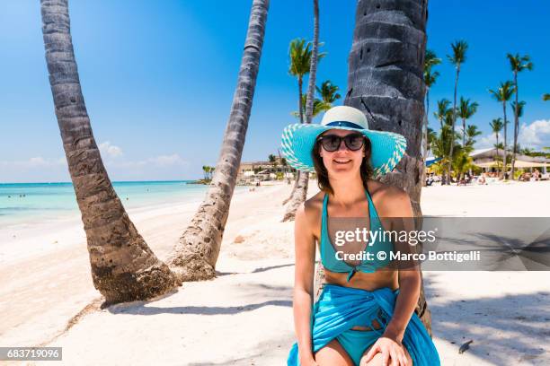 portrait of a mid adult woman leaning on a palm tree. dominican republic. - punta cana stock pictures, royalty-free photos & images