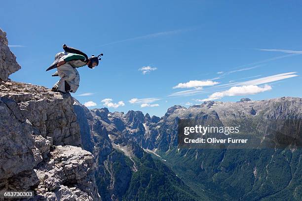 wingsuit base jumper getting ready to jump from cliff, italian alps, alleghe, belluno, italy - sport extreme stock-fotos und bilder