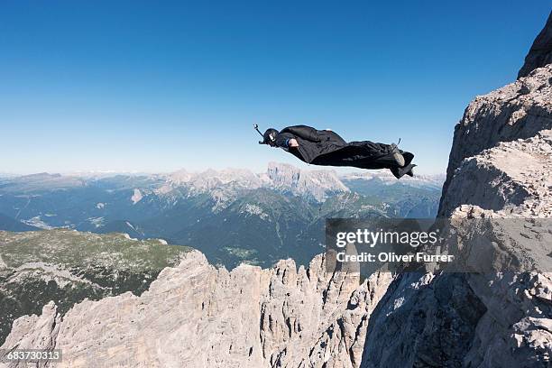 wingsuit base jumper jumping from cliff, italian alps, alleghe, belluno, italy - base jumping stock pictures, royalty-free photos & images