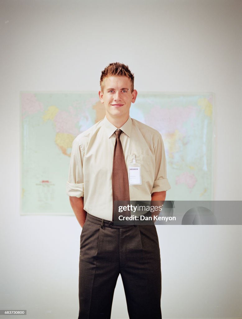 Young man standing in front of wall map with name badge on