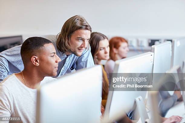 male lecturer showing student using computer in higher education college computer room - students working on pc school stock pictures, royalty-free photos & images