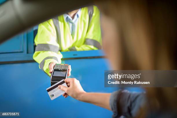 driver in car paying toll booth using contactless card payment technology, close up - peaje fotografías e imágenes de stock