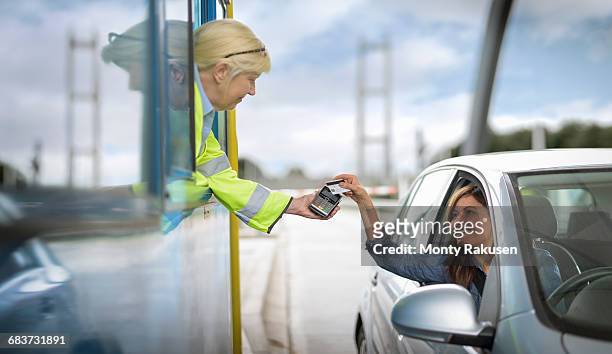 female driver in car paying toll booth at bridge - humber bridge stockfoto's en -beelden