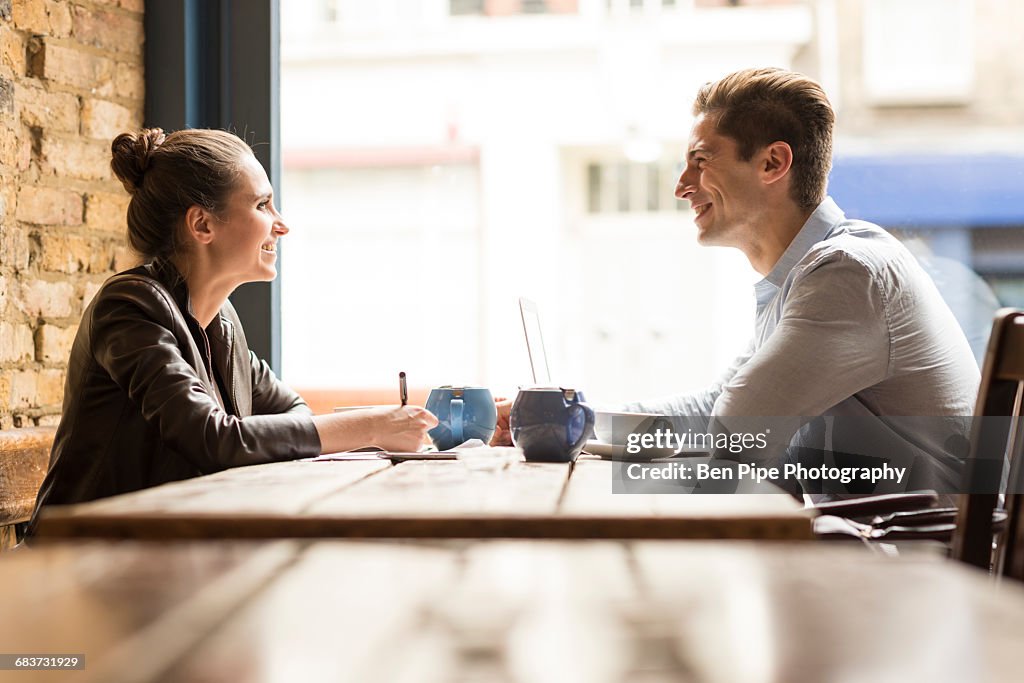 Young businessman and woman meeting in cafe