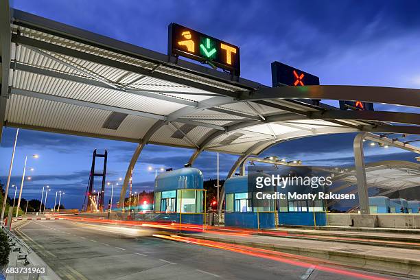 night view of cars passing through toll booth at bridge - humber bridge stock-fotos und bilder