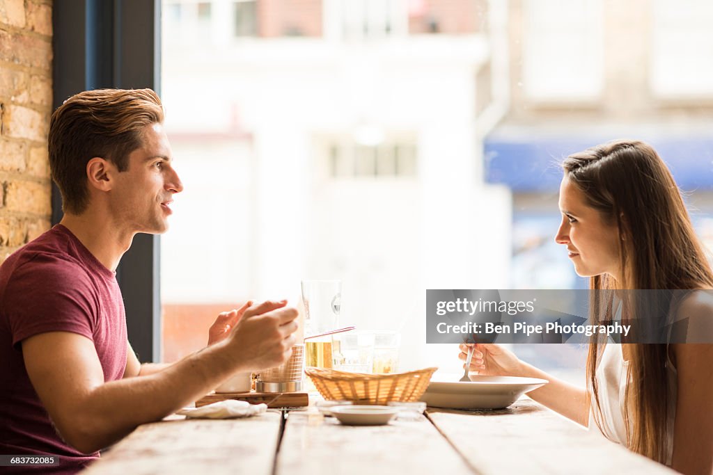 Young couple chatting whilst eating in restaurant