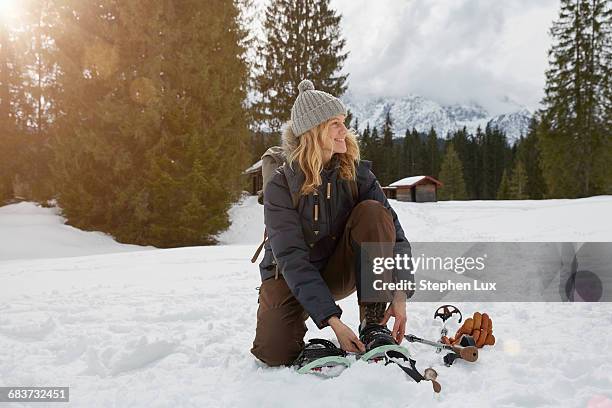 mature woman putting on snow shoes in snowy landscape, elmau, bavaria, germany - sneeuwschoen stockfoto's en -beelden