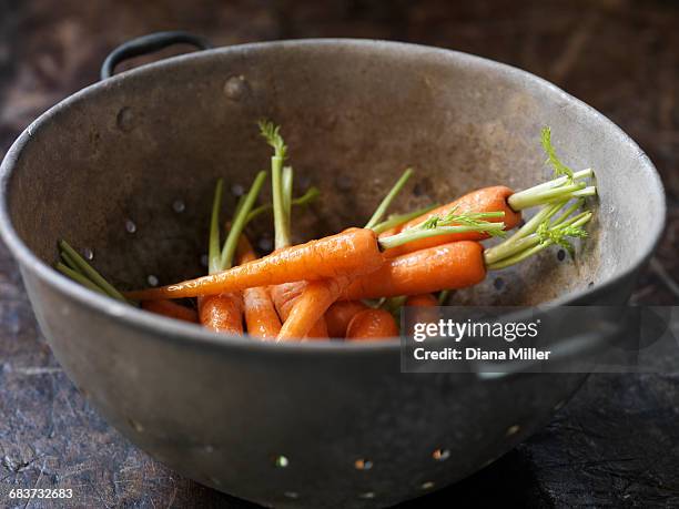 fresh organic vegetables, baby carrots in metal colander - ベビーキャロット ストックフォトと画像