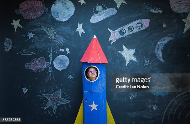 portrait of girl in handmade space rocket in front of space themed chalk drawings - wit blackboard - fotografias e filmes do acervo