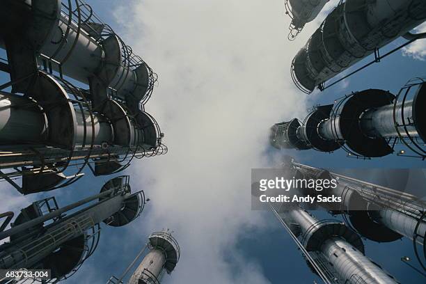 oil refinery,low angle view of stacks emitting smoke - refinaria - fotografias e filmes do acervo