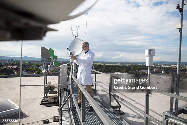 male meteorologist updating meteorological equipment measurements at rooftop weather station - weather station fotografías e imágenes de stock