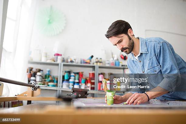 male printer applying green ink to silkscreen in printing press studio - silk screen stock pictures, royalty-free photos & images