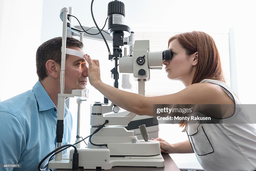 Optician looking into patients eyes at small business opticians
