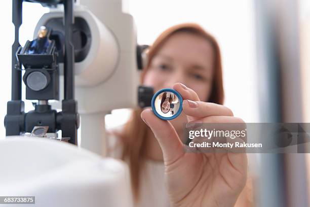 optician holding up lens to patients eyes at small business opticians - looking through lens stock-fotos und bilder