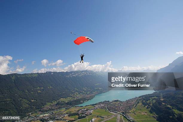 male sky diver with parachute over lake, interlaken, berne, switzerland - confidence male landscape stock-fotos und bilder