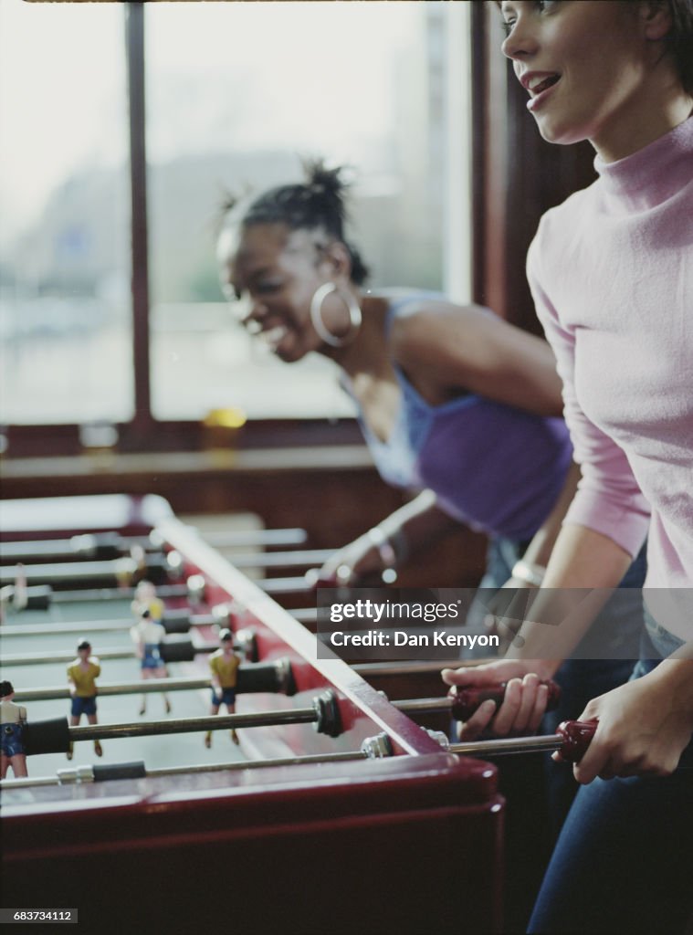 Two young women playing table football