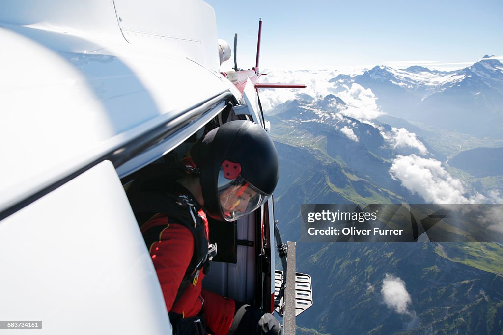 Female sky diver in helicopter checking for exit over mountain, Interlaken, Berne, Switzerland