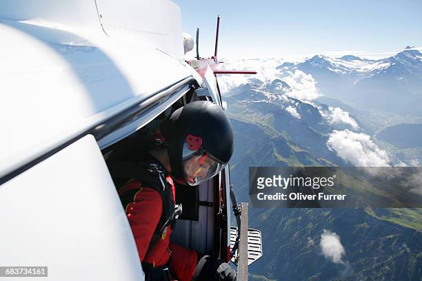 female sky diver in helicopter checking for exit over mountain, interlaken, berne, switzerland - skydiving bildbanksfoton och bilder