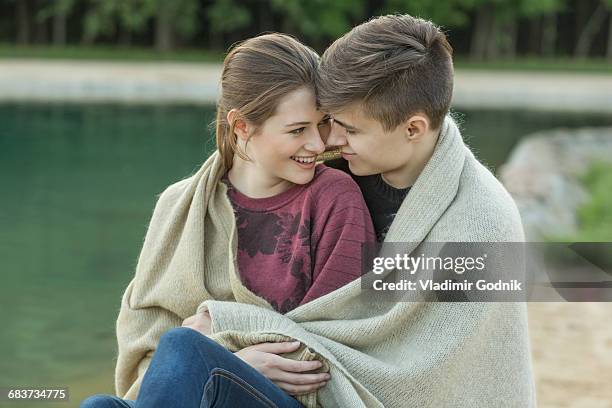 smiling young loving couple wrapped in blanket resting by lake - voronezh stock pictures, royalty-free photos & images