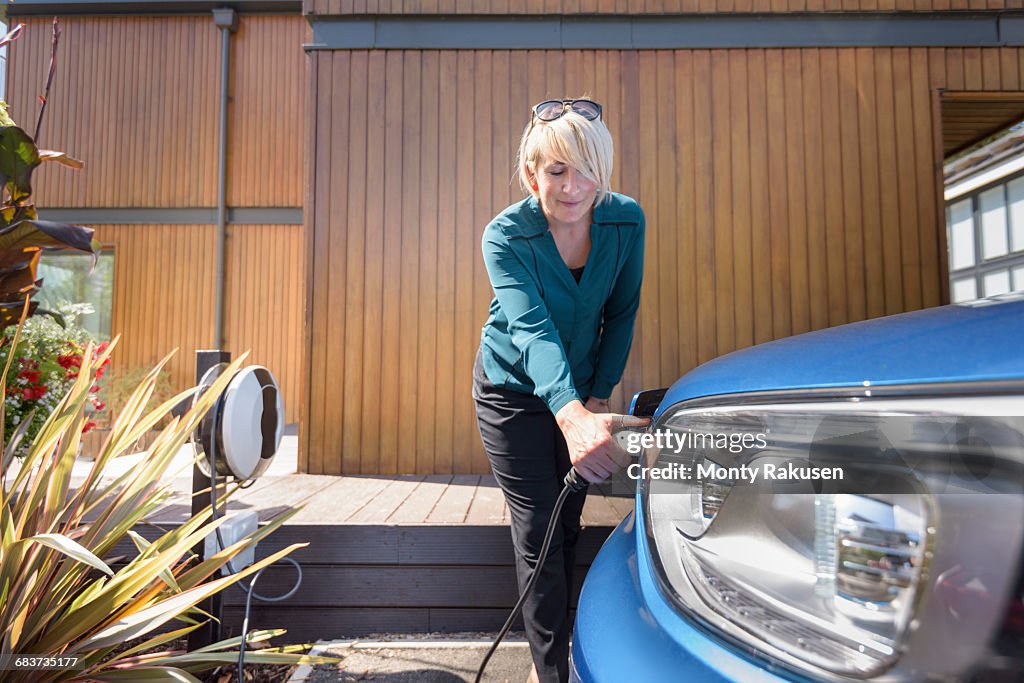 Woman charging electric car from charging point