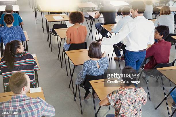 professor collecting test from students in classroom - tentamenzaal stockfoto's en -beelden