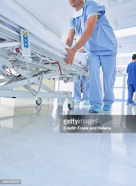 two medics urgently pushing hospital bed along corridor - bett machen stock-fotos und bilder