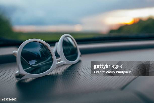 close-up of sunglasses on car dashboard against windshield - armaturenbrett stock-fotos und bilder