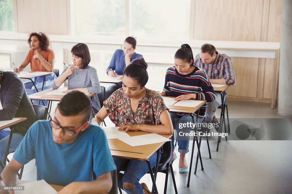 College students taking test at desks in classroom