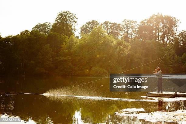 senior man fly fishing on summer lake - fishing line stock pictures, royalty-free photos & images