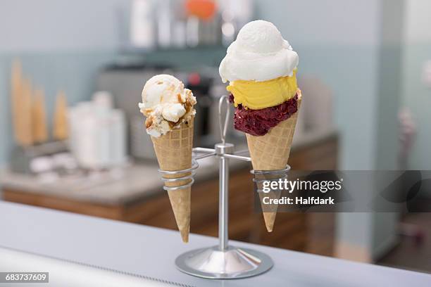various ice cream cones in holder on counter at store - ice cream counter stock-fotos und bilder