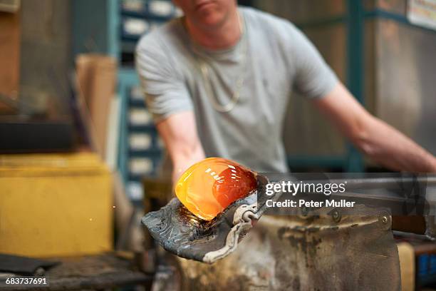 glassblower in workshop forming molten glass on blowpipe - glass blowing stock pictures, royalty-free photos & images