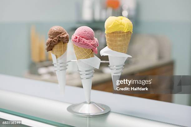 various ice cream cones in spiral holder on counter at store - ice cream scoop stock pictures, royalty-free photos & images