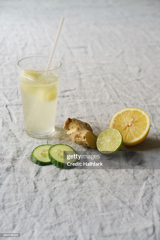 Glass of lemonade with ginger, cucumber and lime on tablecloth