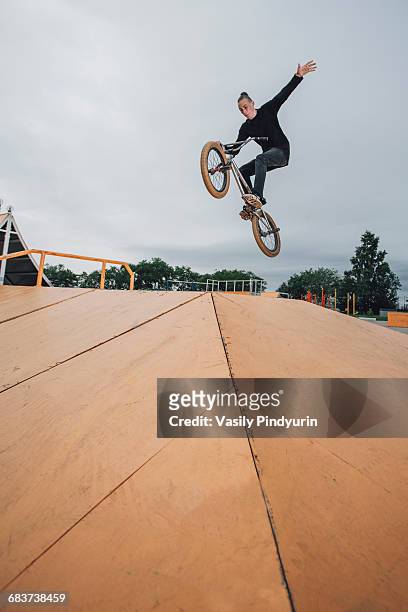 teenager performing stunt on bmx bicycle at skateboard park - bicycle stunt stock pictures, royalty-free photos & images