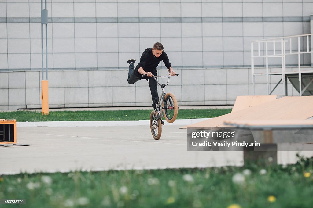 Teenager performing wheelie with bicycle at skateboard park