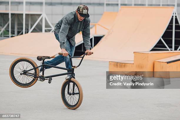 teenager performing wheelie with bicycle at skateboard park - スタントバイク ストックフォトと画像