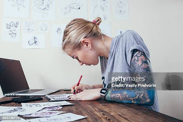confident tattoo artist working on designs by laptop at art studio - tatouage femme photos et images de collection