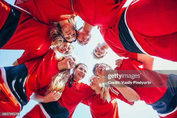 cheerful soccer players talking while huddling against clear sky - équipe sportive photos et images de collection