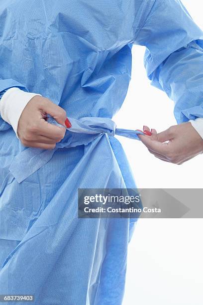 surgeon tying belt on surgical scrub - operating gown stock pictures, royalty-free photos & images