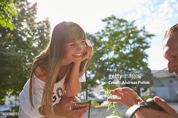 young couple outdoors, listening to music through earphones - andreas pollok stock-fotos und bilder