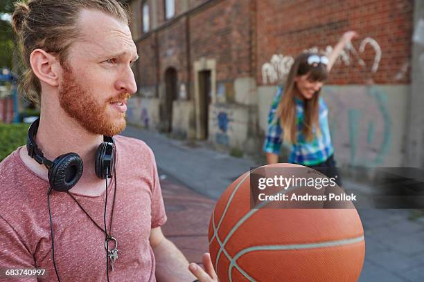 young couple outdoors, throwing basketball - andreas pollok stock-fotos und bilder