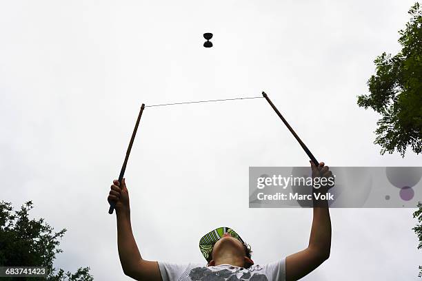 low angle view of boy playing with diabolo against sky - yo yo stock pictures, royalty-free photos & images