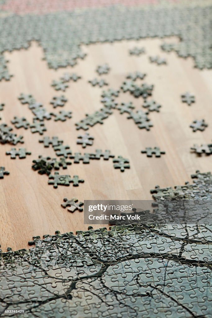 High angle view of jigsaw puzzle and pieces on wooden table