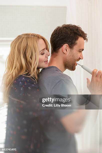 couple in bathroom brushing teeth - elektrische zahnbürste stock-fotos und bilder