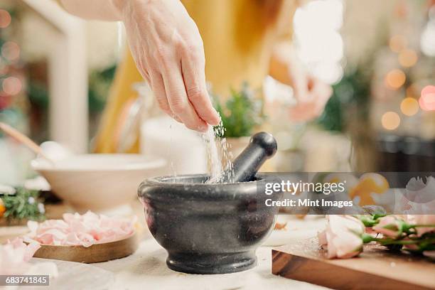 a hand adding ingredients to a pestle and mortar on a kitchen counter. - mortel bildbanksfoton och bilder