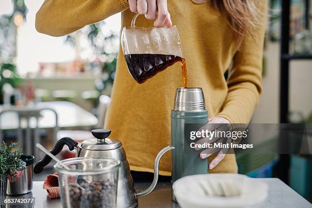 a woman pouring coffee into a flask. - flask imagens e fotografias de stock