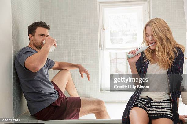 couple in bathroom brushing teeth - couple brushing teeth stock pictures, royalty-free photos & images